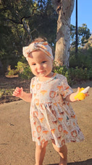 Baby girl wearing Wild Team organic cotton bow accessory with the dress set