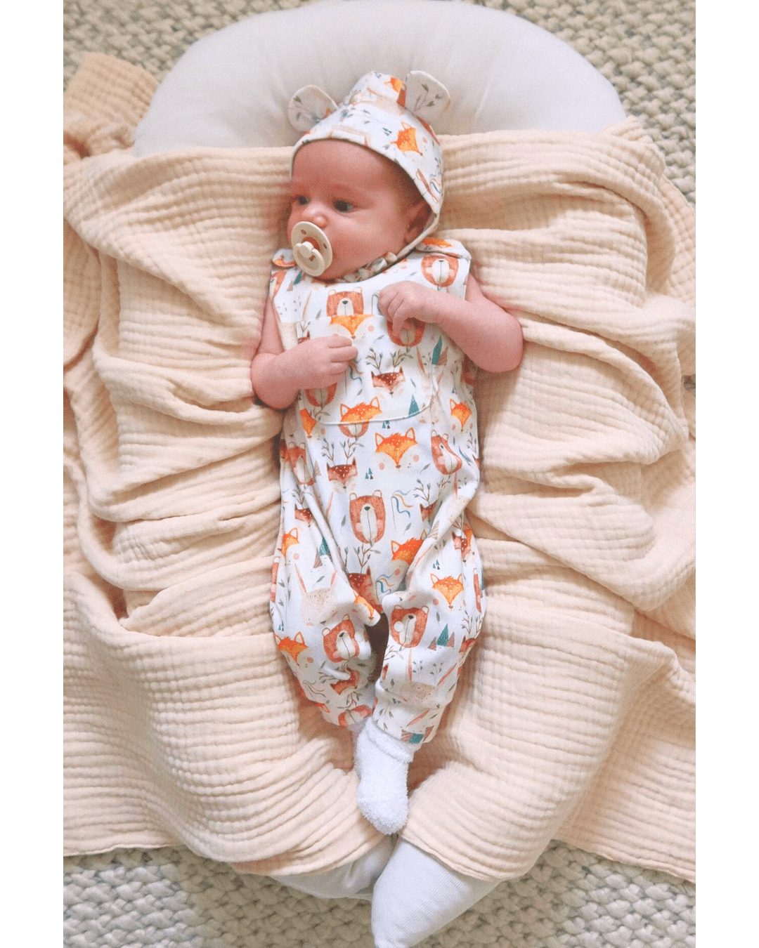 Baby wearing Wild Team organic long leg romper and matching bonnet brand Duper DuDu design by a NICU nurse