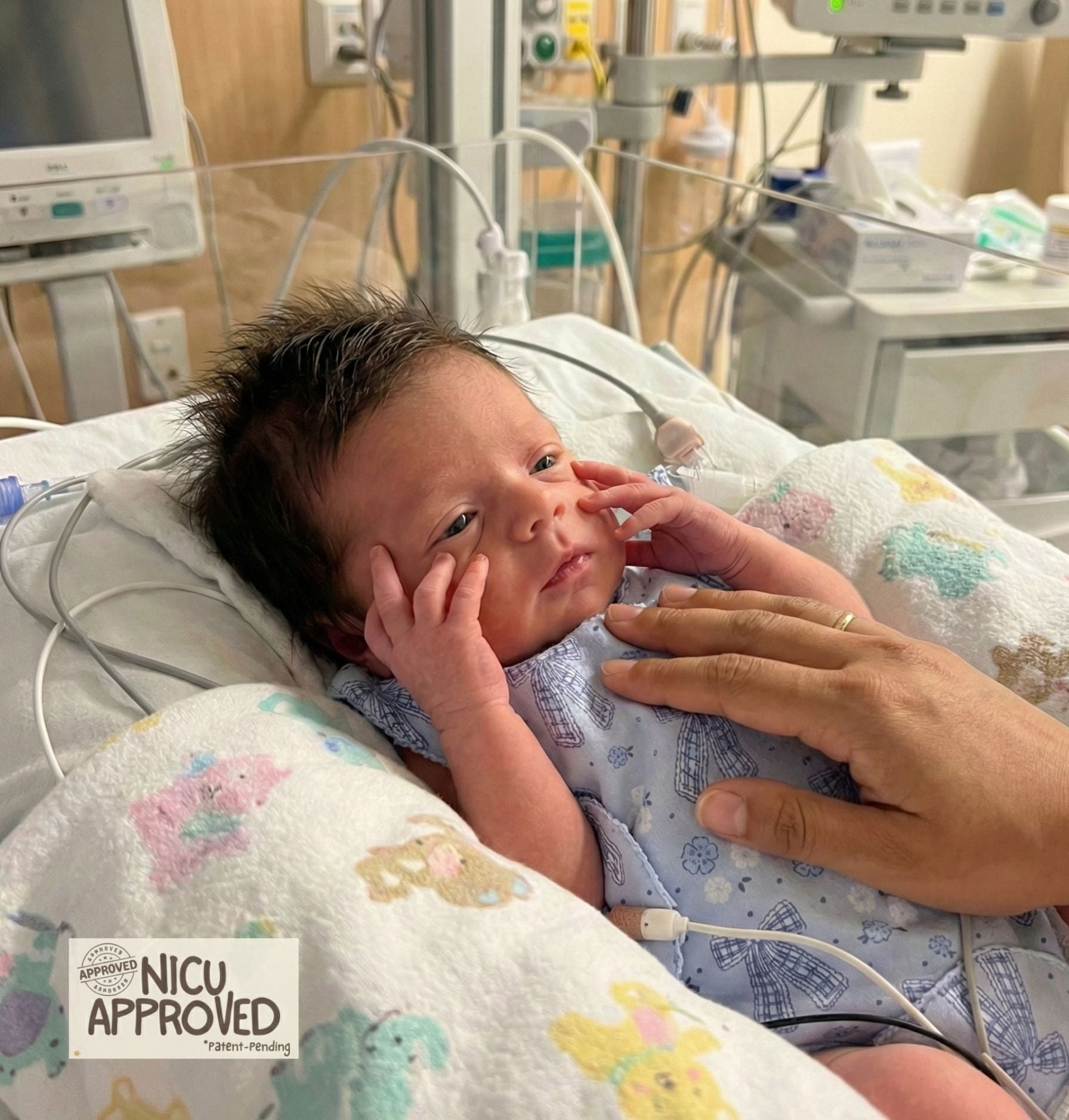 Peaceful premature baby sleeping in hospital crib. Wearing soft organic cotton adaptive Duper DuDu onesie in Bowy print. NICU Approved for comfort.